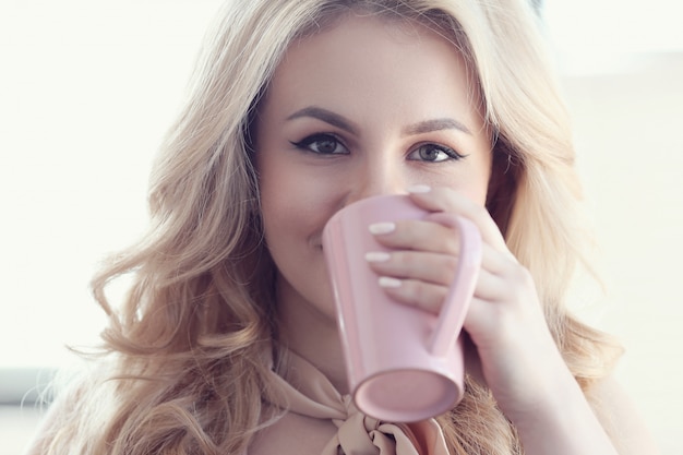 szczera piękna blondynki kobieta pije herbatę lub filiżankę kawy