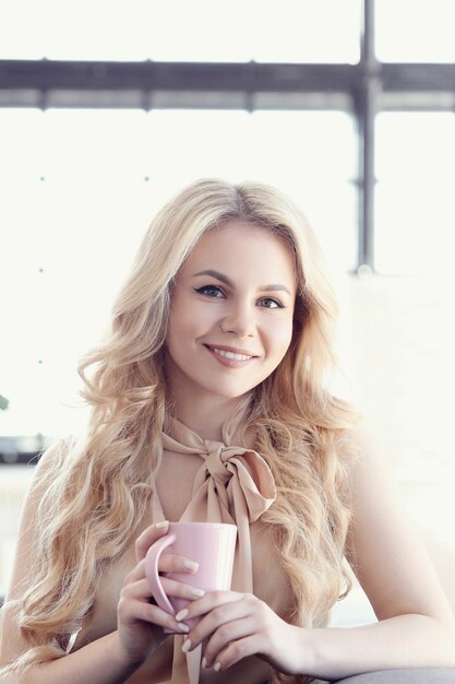 szczera piękna blondynki kobieta z filiżanką herbaty lub kawy