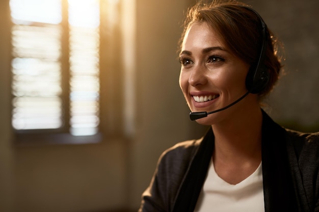 Bezpłatne zdjęcie szczęśliwa agentka call center nosząca zestaw słuchawkowy podczas pracy w biurze