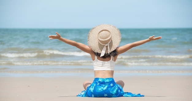 Szczęśliwa azjatycka kobieta uśmiecha się i bawi na plaży