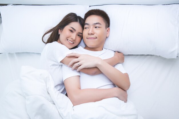 Szczęśliwa Azjatycka para na łóżku w domu