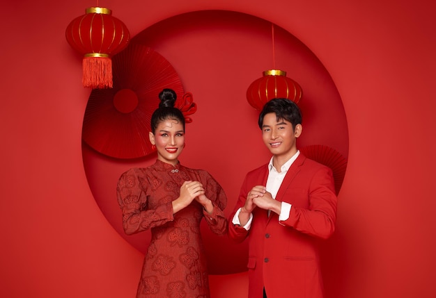 Szczęśliwa Azjatycka Para W Czerwonym, Swobodnym Stroju Z Gestem Gratulacyjnym Powitania Szczęśliwego Nowego Roku 2023