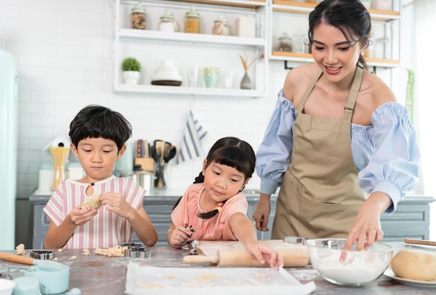 Szczęśliwa azjatycka rodzina przyrządzająca jedzenie w domowej kuchni Ciesz się wspólną aktywnością rodzinną