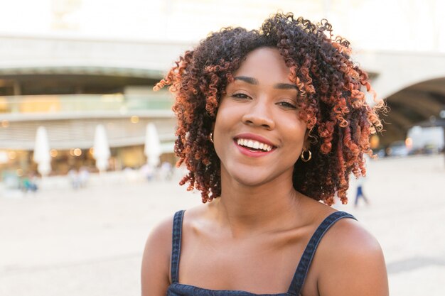 Szczęśliwa beztroska amerykanin afrykańskiego pochodzenia dama pozuje w miasto kwadracie