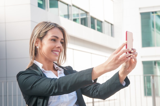 Szczęśliwa biznesowa kobieta opowiada selfie fotografię outdoors