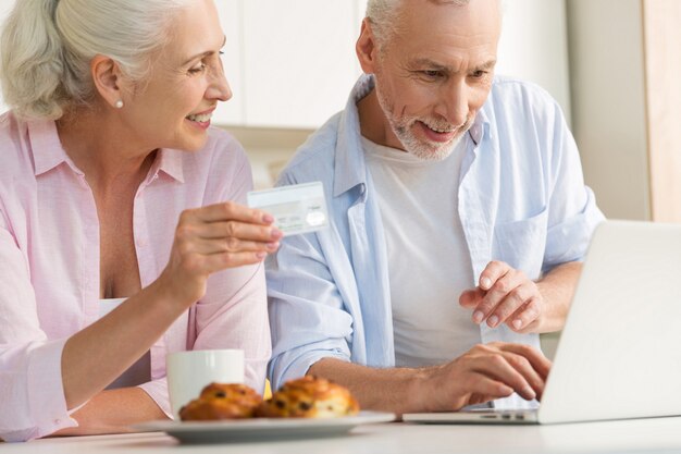 Szczęśliwa dojrzała kochająca pary rodzina używa laptop trzyma kredytową kartę