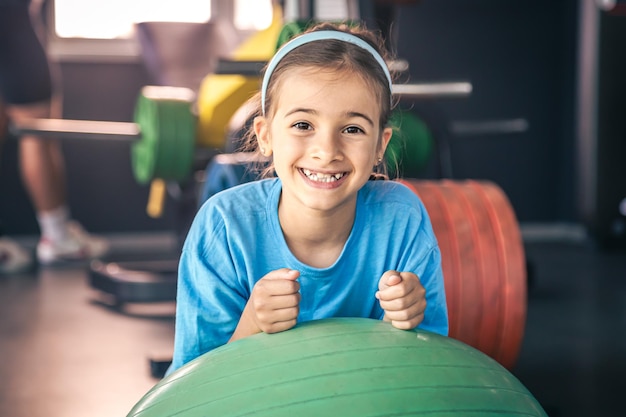 Szczęśliwa dziewczyna rozciąga swoje ciało na fitball na siłowni