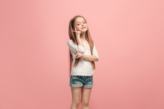 Szczęśliwa dziewczyna stojąc, uśmiechając się na białym tle na modnym różowym studio