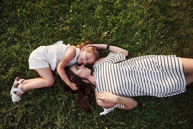 Szczęśliwa dziewczynka i jej matka, zabawy na świeżym powietrzu na zielonej trawie w słoneczny letni dzień.