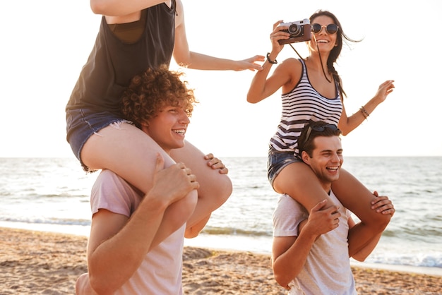 Szczęśliwa Grupa Przyjaciół Kochających Pary Spaceru Na świeżym Powietrzu Na Plaży Zabawy Kobieta Trzyma Aparat Fotograficzny. Premium Zdjęcia