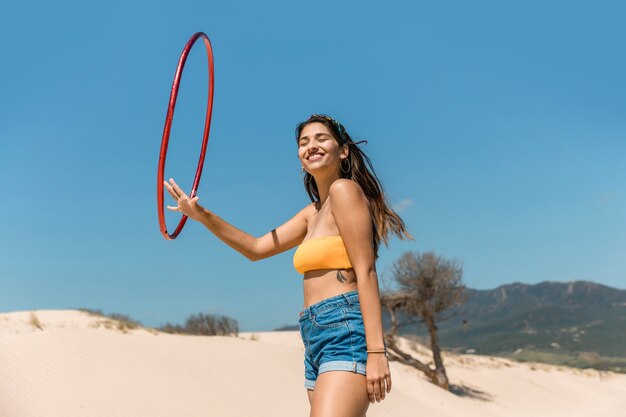 Szczęśliwa kobieta bawić się z hula obręczem na piasku