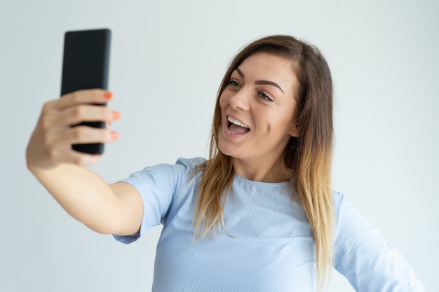 Szczęśliwa kobieta bierze selfie fotografię na smartphone. Szczęśliwa dama ma zabawę.