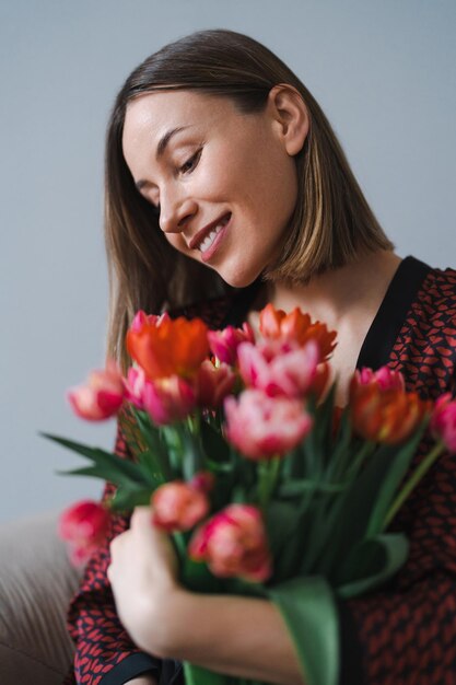 Szczęśliwa kobieta cieszy się bukietem tulipanów Gospodyni ciesząca się bukietem kwiatów i wnętrzem kuchni Słodki dom Bez alergii