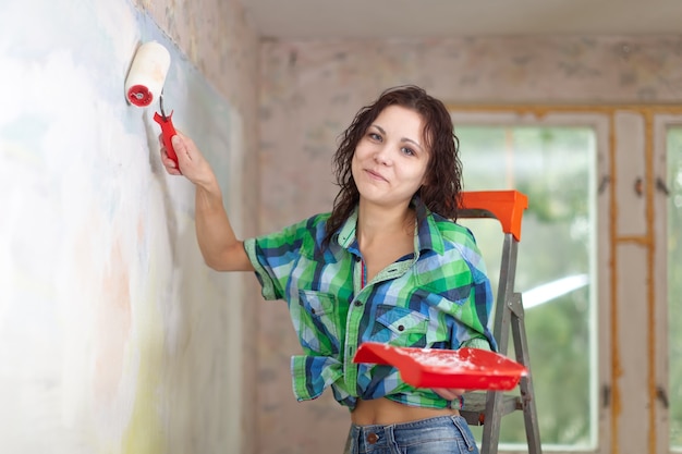 Szczęśliwa kobieta maluje ścianę