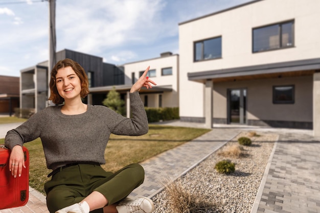 Szczęśliwa Kobieta Na Tle Nowego Domu. Portret Kupującego Po Raz Pierwszy, Właściciela Domu, Najemcy Mieszkania, Najemcy Mieszkania Lub Gospodyni. Dzień Przeprowadzki I Zakup Własnej Koncepcji Nieruchomości.