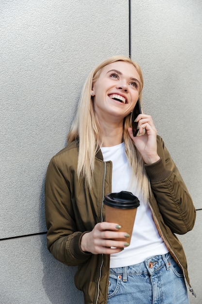 Bezpłatne zdjęcie szczęśliwa kobieta opowiada na smartphone z kawą