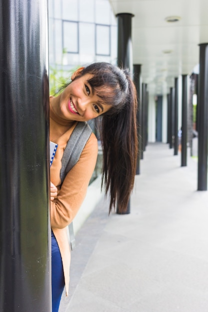 Bezpłatne zdjęcie szczęśliwa kobieta podglądające z kolumny
