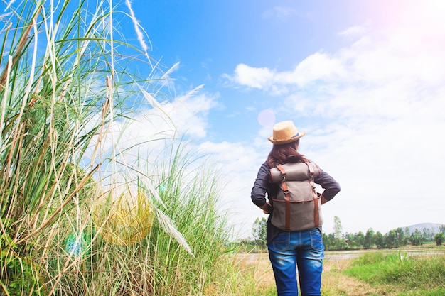 Szczęśliwa kobieta podróżnik patrząc na błękitne niebo z pola traw, koncepcja podróży wanderlust, miejsce na tekst