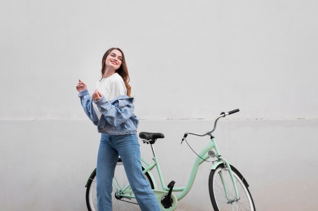Szczęśliwa kobieta pozuje obok swojego roweru na zewnątrz