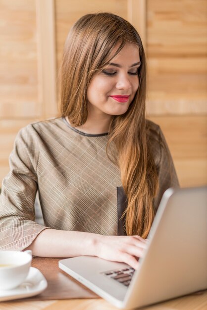 Szczęśliwa kobieta pracuje z jej laptopa