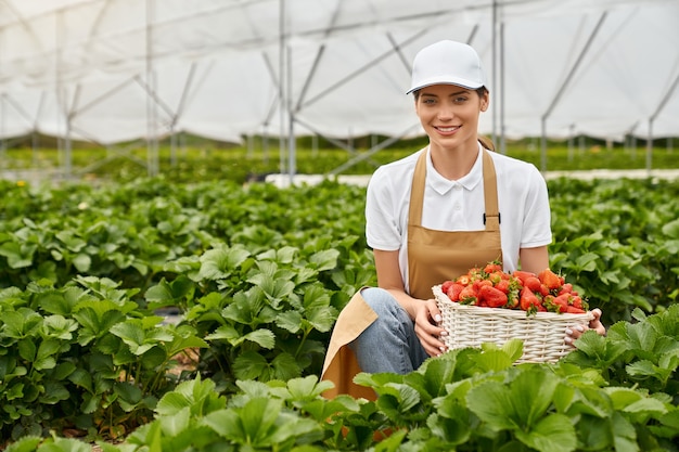 Bezpłatne zdjęcie szczęśliwa kobieta rolnik uśmiecha się i trzyma świeżą truskawkę