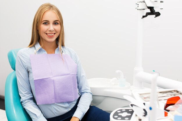 Szczęśliwa kobieta siedzi w krześle przy dentysty biurem
