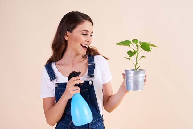 Szczęśliwa kobieta spryskuje rośliny sprayem owadobójczym