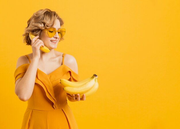 Szczęśliwa kobieta używa banana jako telefon