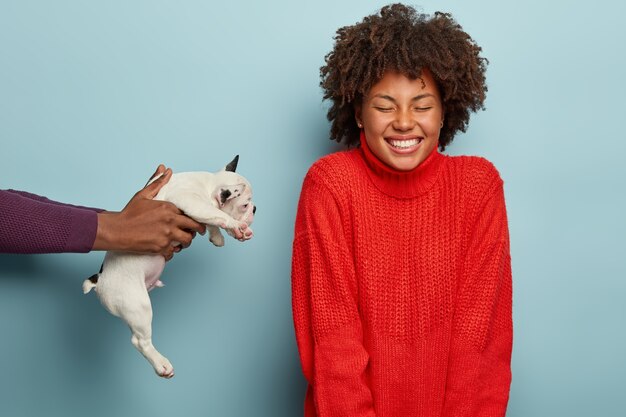 Szczęśliwa kobieta w czerwonym swetrze otrzymującym szczeniaka