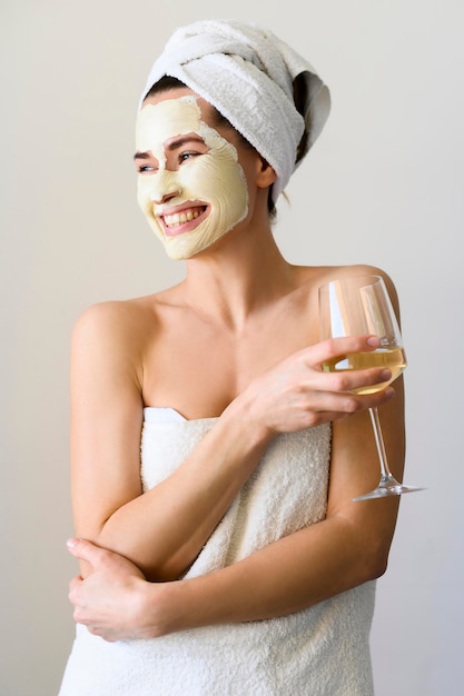 Szczęśliwa kobieta z twarzy maską cieszy się szkło wino