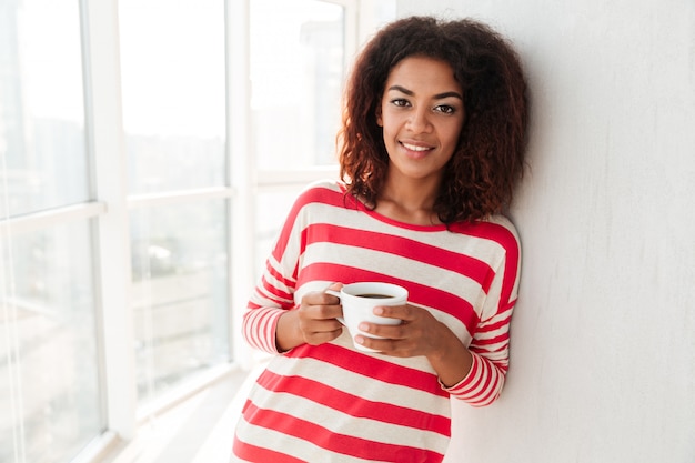 Szczęśliwa ładna Afrykańska Kobieta Pije Kawę Blisko Okno