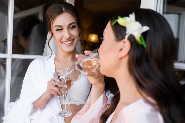 Szczęśliwa ładna panna młoda kobieta patrząc na druhnę pijącą świętującą wieczór panieński Piękne dziewczyny przygotowujące się do ślubu snading na balkonie Poranek panny młodej Specjalne wydarzenie