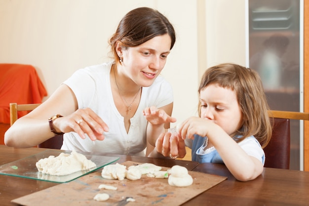 Szczęśliwa matka i dziecko rzeźbi z plasteliny lub ciasta w domu