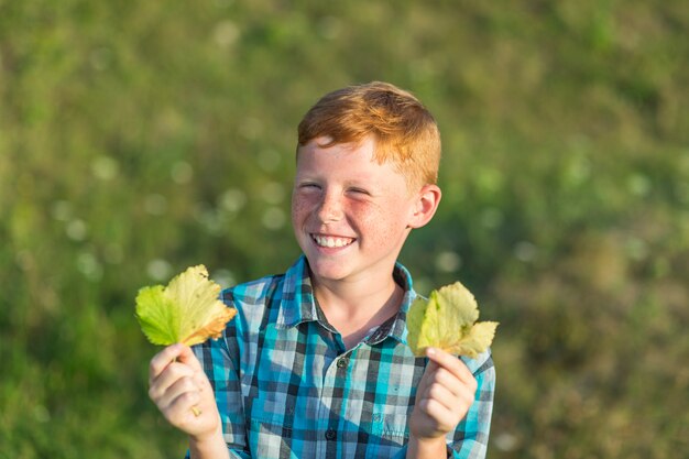 Szczęśliwa młoda chłopiec trzyma jesień liście
