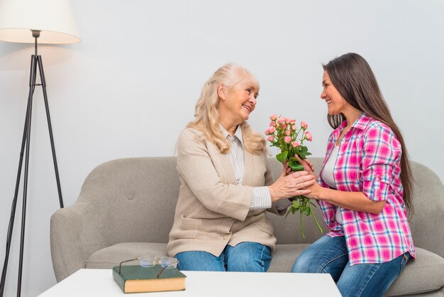 Szczęśliwa młoda córka daje senior matki kwiatu bukietowi