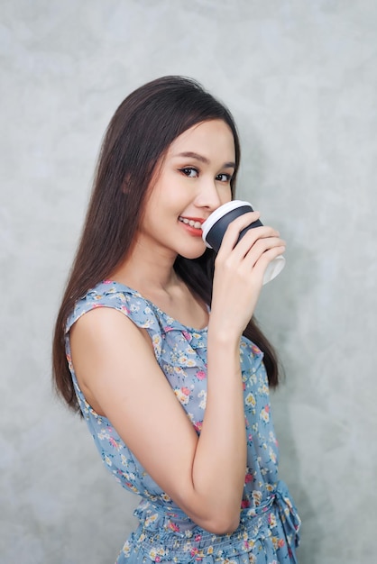 Szczęśliwa młoda dorosła kobieta trzyma filiżankę kawy rano