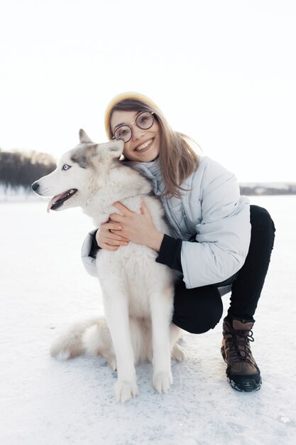 Szczęśliwa młoda dziewczyna bawić się z siberian husky psem w zima parku