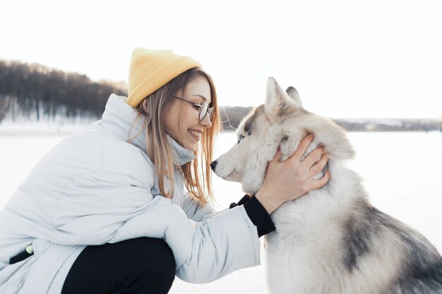 Szczęśliwa młoda dziewczyna bawić się z siberian husky psem w zima parku
