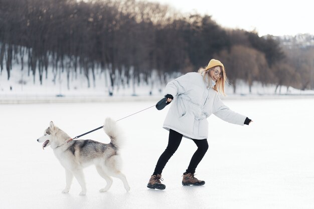 Szczęśliwa młoda dziewczyna bawić się z siberian husky psem w zima parku