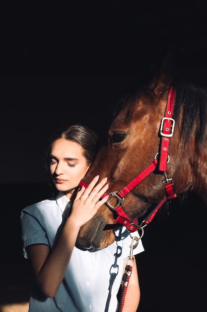 Szczęśliwa młoda dziewczyna siedzi outdoors ściskający jej konia