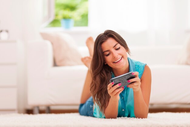 Szczęśliwa młoda kobieta wiadomości tekstowych w domu