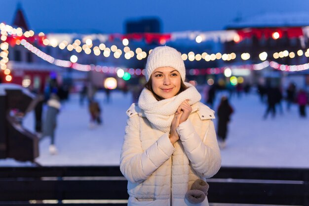 Szczęśliwa młoda kobieta zimą w pobliżu lodowiska koncepcja świąteczno-zimowa