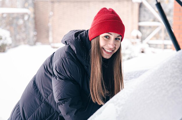 Szczęśliwa młoda kobieta zimą wyciąga coś z bagażnika samochodu