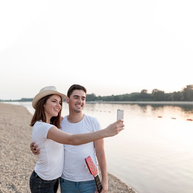 Szczęśliwa młoda para bierze selfies przy zmierzchem