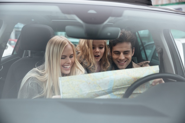 Szczęśliwa młoda rodzina w samochodowej mienie mapie.
