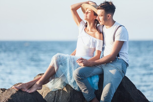 Szczęśliwa młoda romantyczna para relaksuje na plaży i ogląda zmierzch