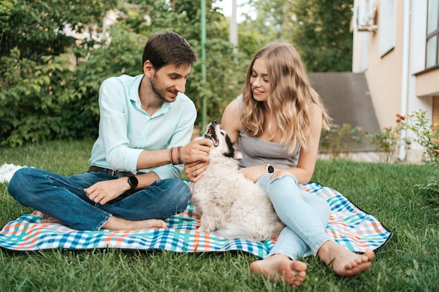 Szczęśliwa para facetów bawiących się z psem na podwórku na trawie. Wesoły stary pies