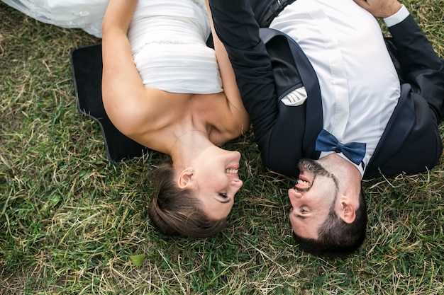Bezpłatne zdjęcie szczęśliwa para nowożeńcy leżąc na trawie i patrząc na siebie