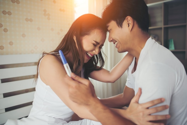 Szczęśliwa para ono uśmiecha się po znajduje out pozytywnego ciążowego test w sypialni