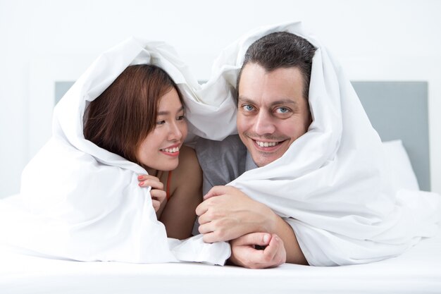 Szczęśliwa para owinięta w koc w łóżku